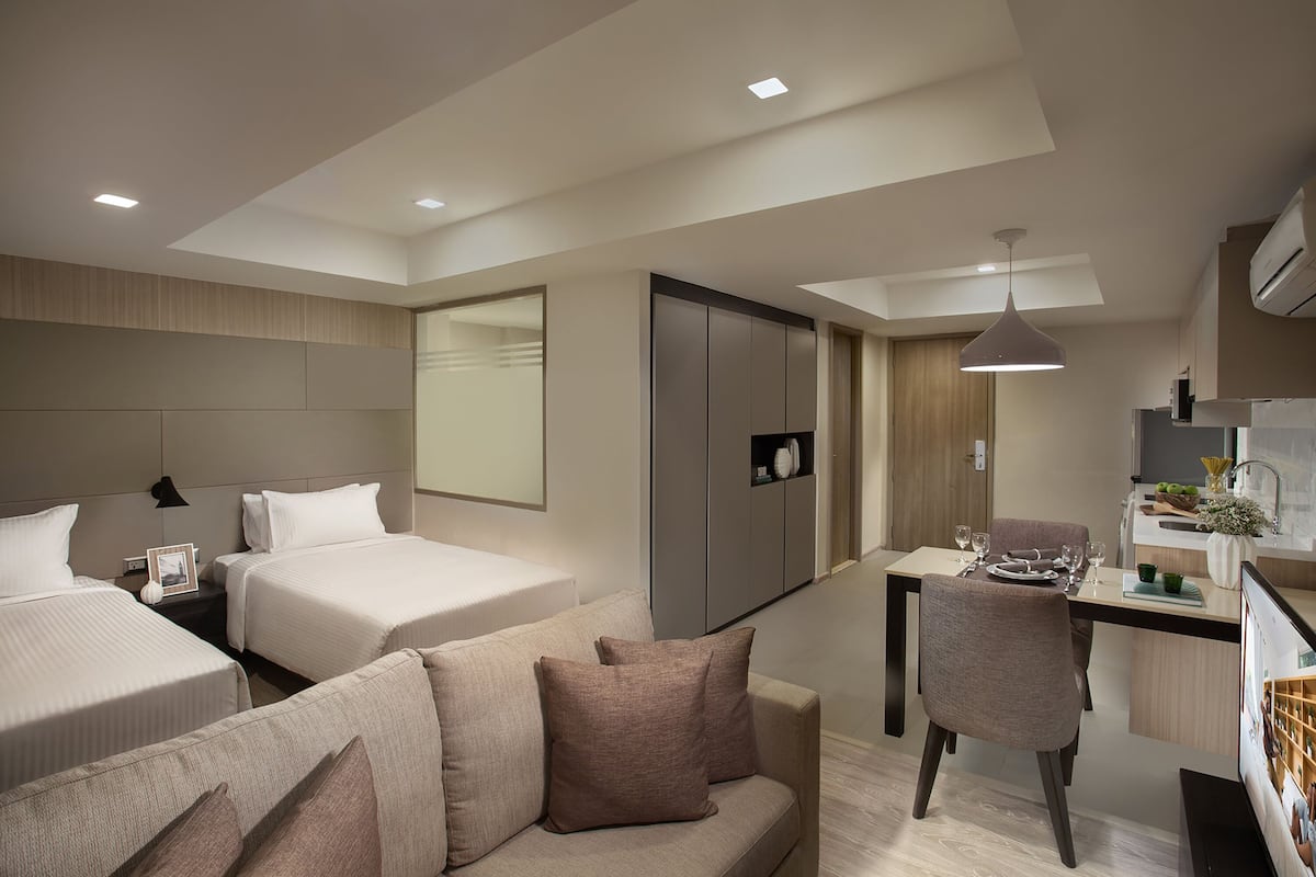 Una habitación de hotel moderna con dos camas, un sofá, un comedor y una kitchenette.