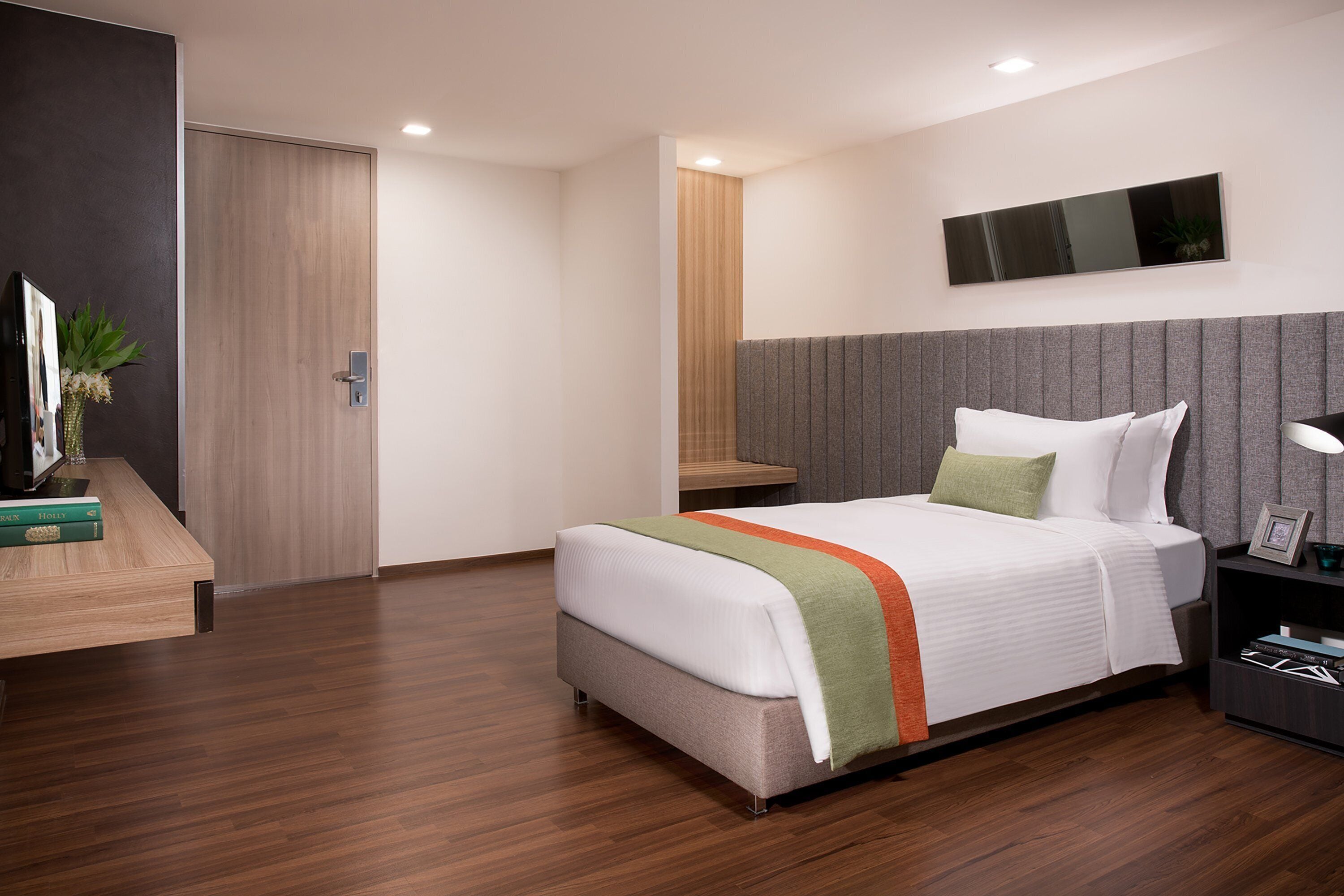 Une chambre d’hôtel moderne équipée d’un lit, d’une table de chevet et d’un téléviseur à écran plat.