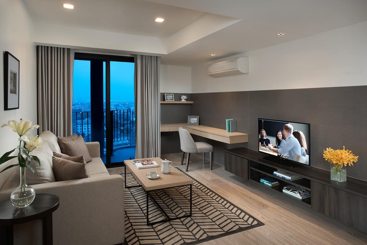 Una sala de estar moderna con sofá, mesa de centro, televisión y vistas al balcón.