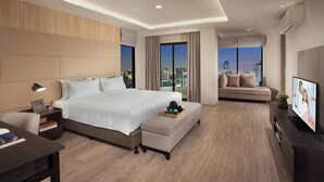 Une chambre d’hôtel moderne dotée d’un grand lit, d’un canapé, d’une télévision et offrant une vue sur la ville.
