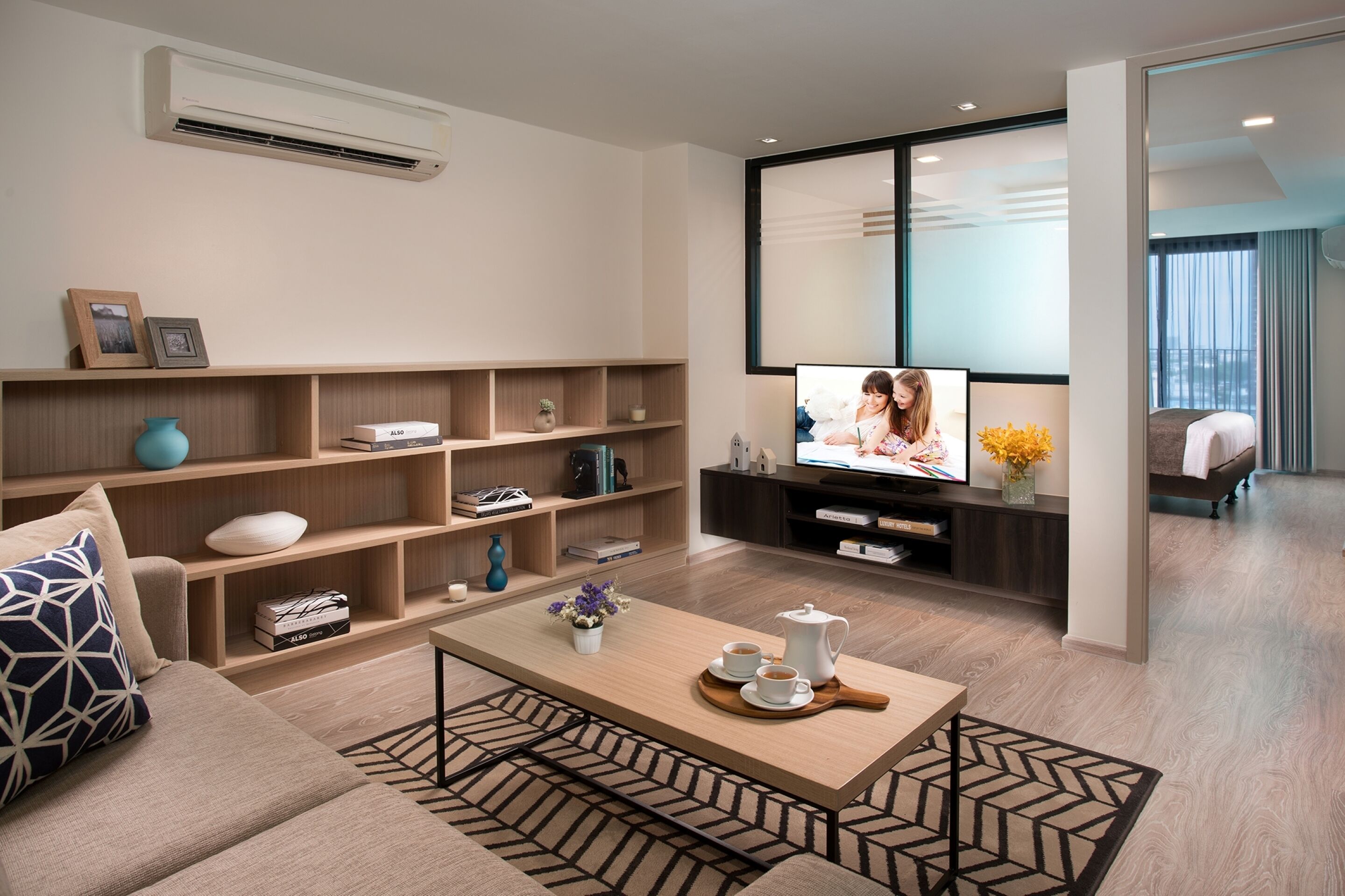 A modern living room with a sofa, coffee table, and shelves with books and decorative items.