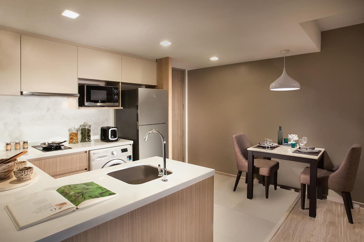 Una cocina moderna con una isla central, electrodomésticos integrados y un comedor con mesa y sillas.