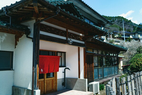 A traditional Japanese house with a wooden exterior, a tiled entrance, and a red towel hanging on the door. - Kominka Yado LOOF Sakanoie (Fuefuki)