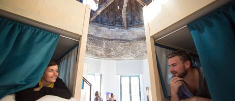 Un dormitorio con literas, techo rústico y ventana.