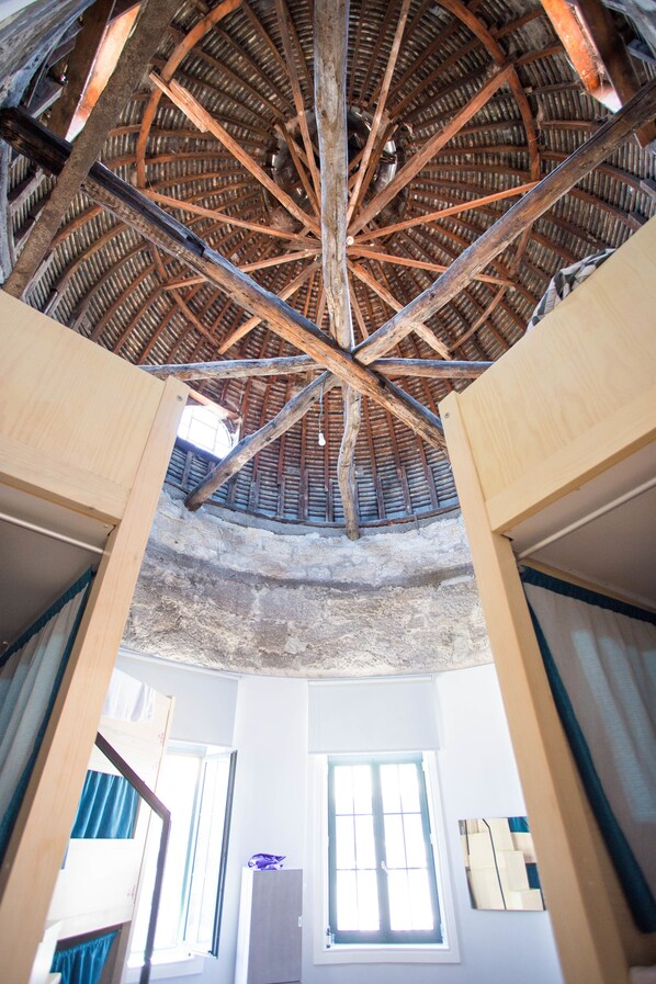 A room with a high wooden ceiling, a window, and a door.