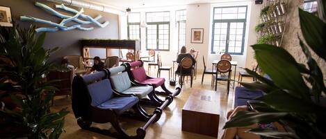 A spacious room with wooden flooring, a large window, and a seating area with chairs and a sofa.