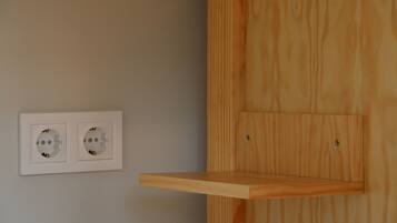 A wall-mounted electrical outlet with a wooden shelf.