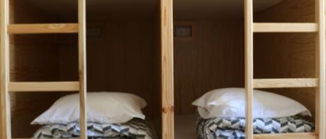 A bunk bed with two levels, each with a pillow and a blanket.