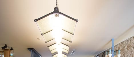 A restaurant with a long wooden table, chairs with smiley faces, and a hanging light fixture.