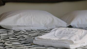 Una cama con almohadas blancas y una manta estampada.