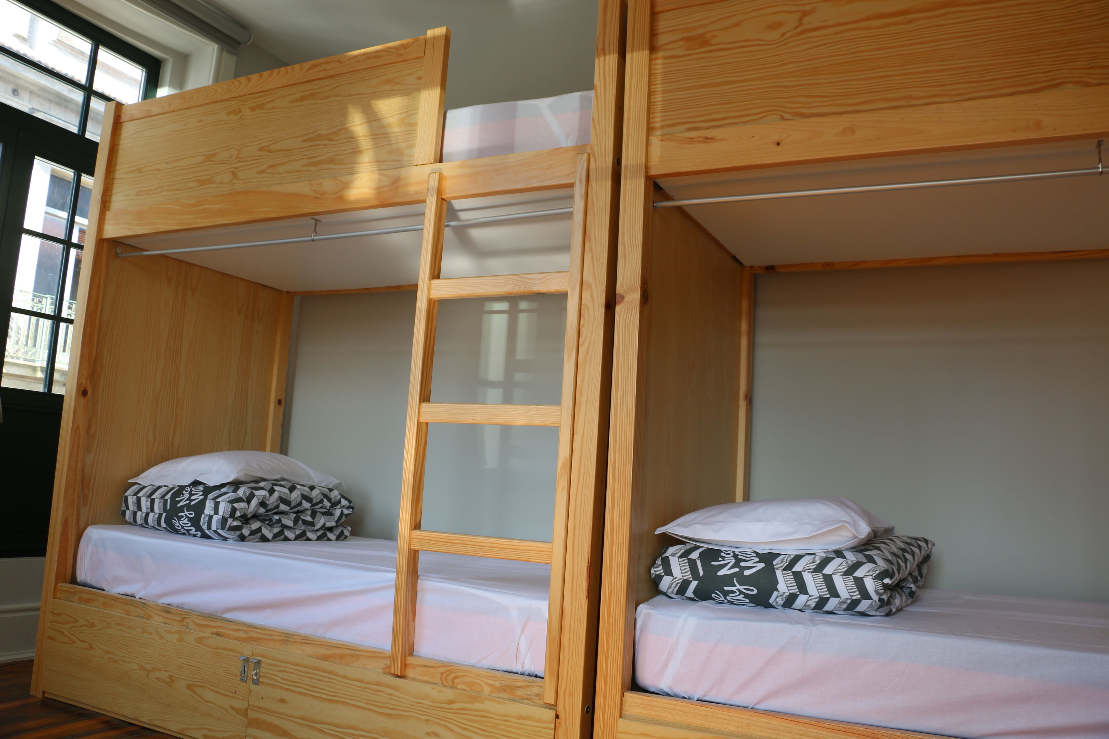 A bunk bed with a ladder, two pillows, and a window.