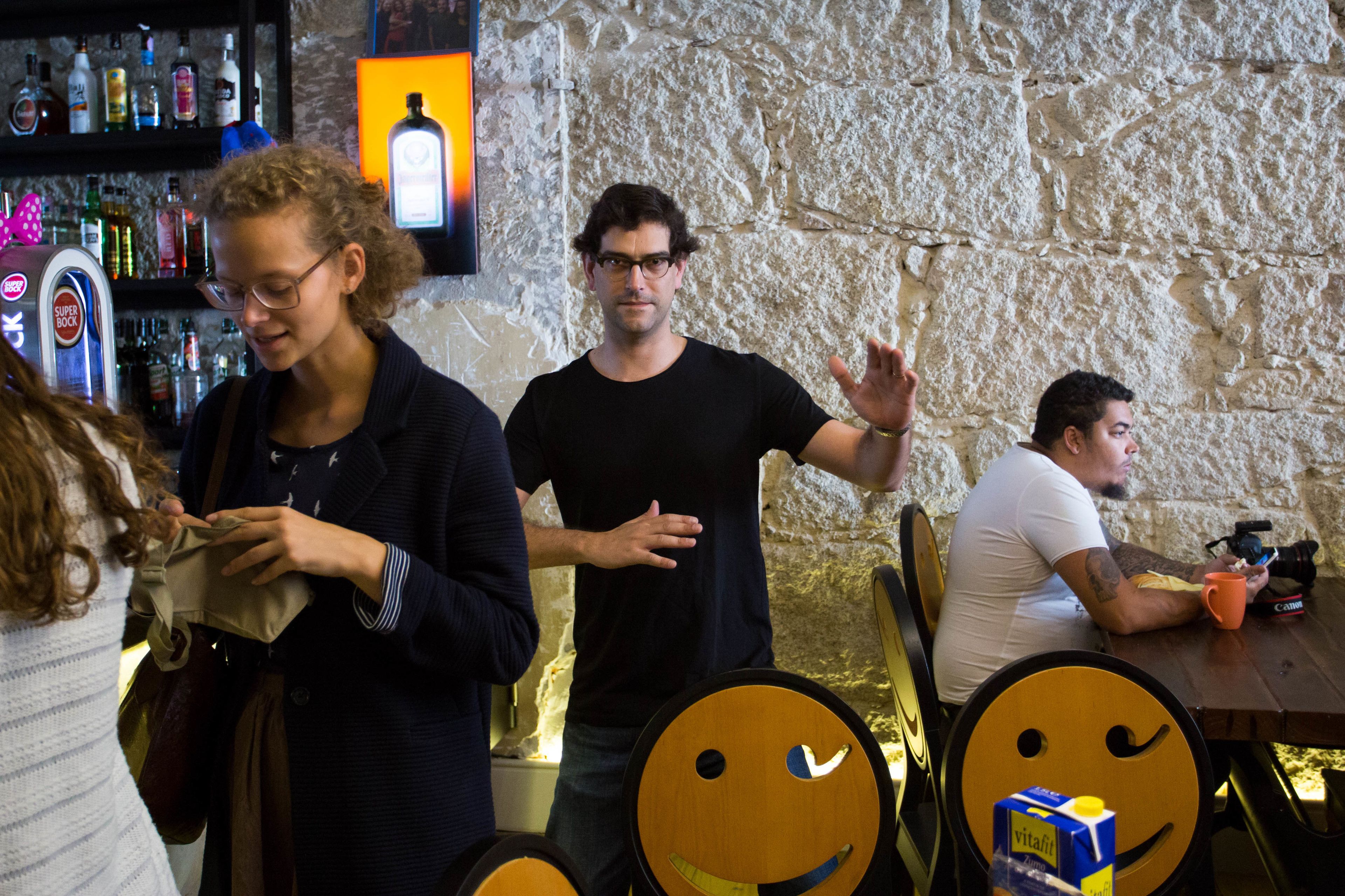 Un bar con pared de piedra, mesas de madera y un sillón con forma de cara sonriente.