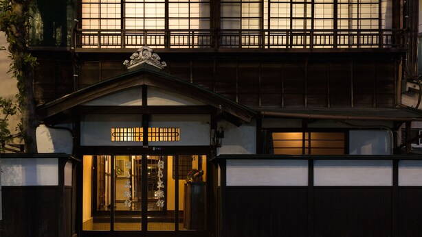 Un edifici tradicional japonès amb façana de fusta i una entrada espaiosa.