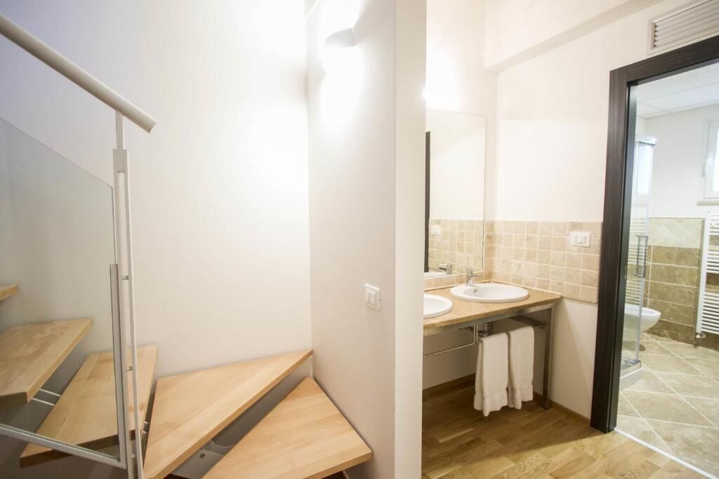 A modern bathroom with a wooden vanity, two sinks, and a mirror.