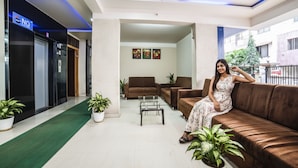 A lobby with a brown sofa, a coffee table, and potted plants. There are three framed artworks on the wall. - FabHotel Imperio (Pune)