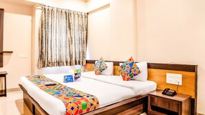 A hotel room with a large bed, a bedside table with a phone, and a curtain. - FabHotel Imperio (Pune)