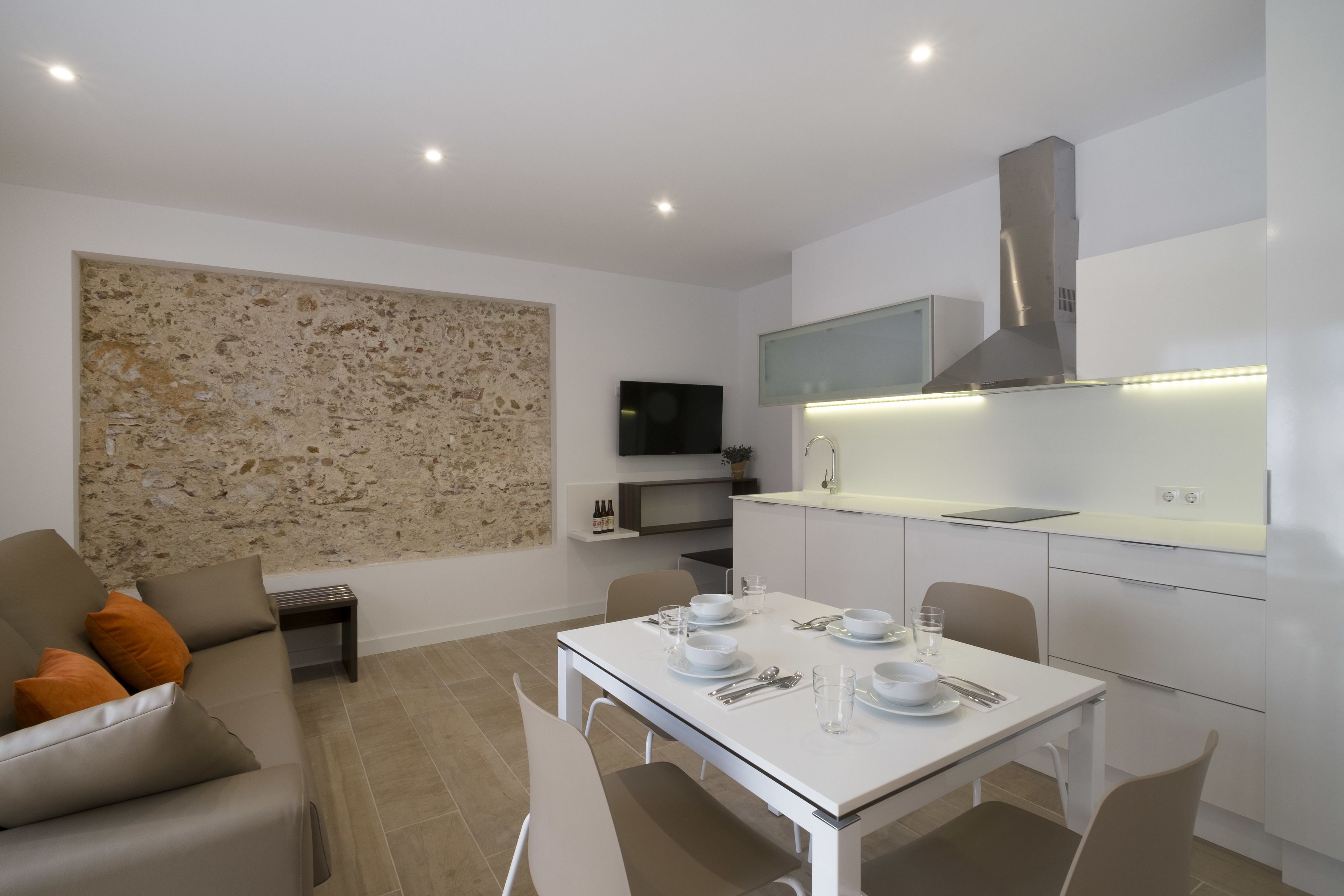 A modern kitchen with white cabinets, a built-in microwave, and a stainless steel range hood.