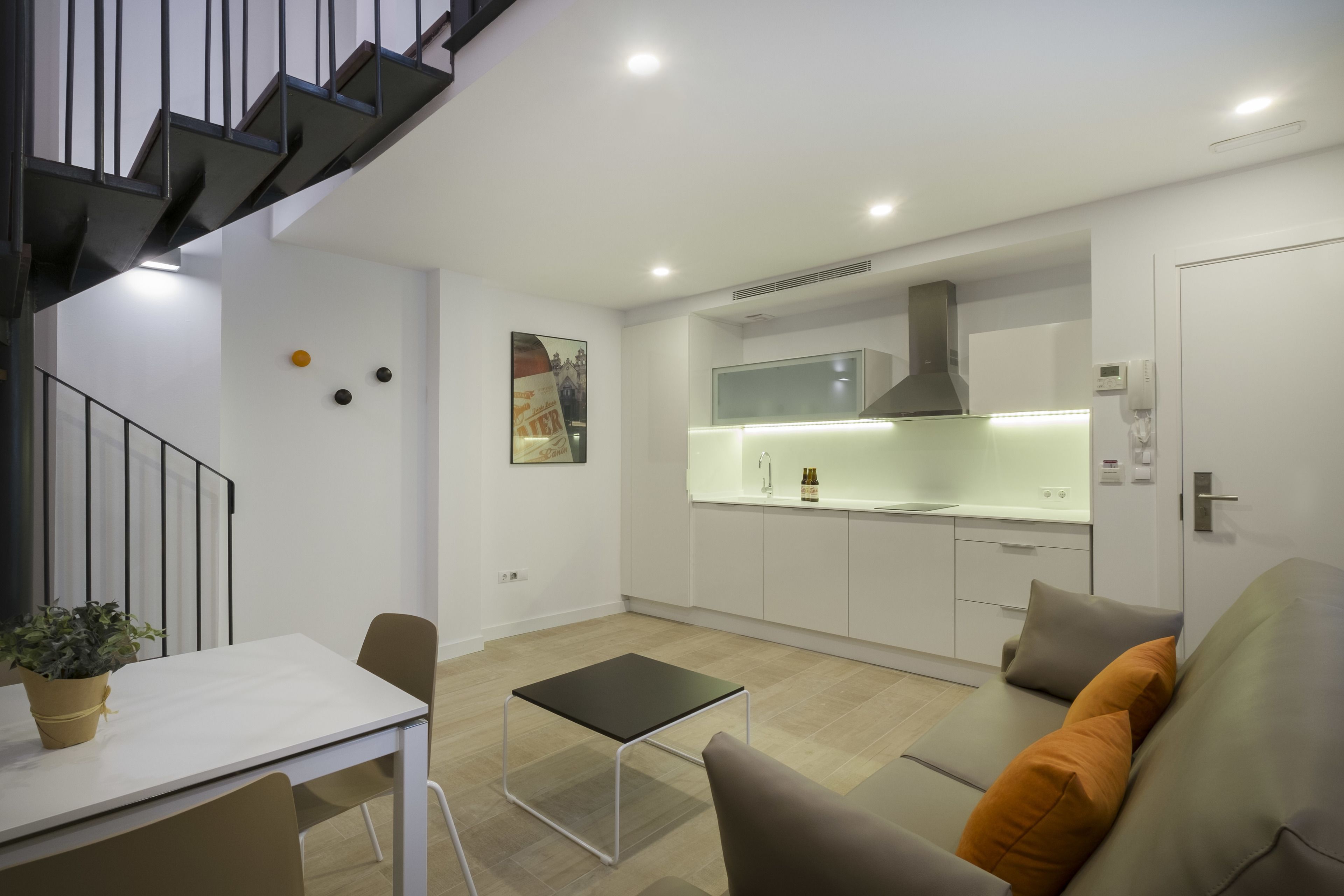 A modern apartment with a kitchen, dining area, and a staircase.