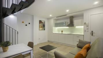 A modern apartment with a kitchen, dining area, and a staircase.