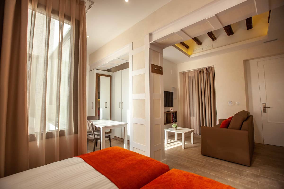 Ein Hotelzimmer mit Bett, Sofa, Schreibtisch und Fernseher.