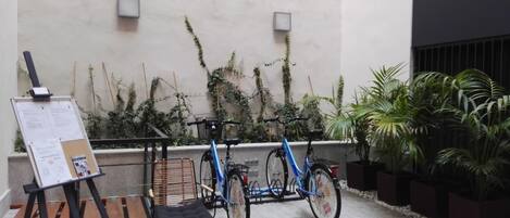 A courtyard with a bicycle, a chair, and a bulletin board.