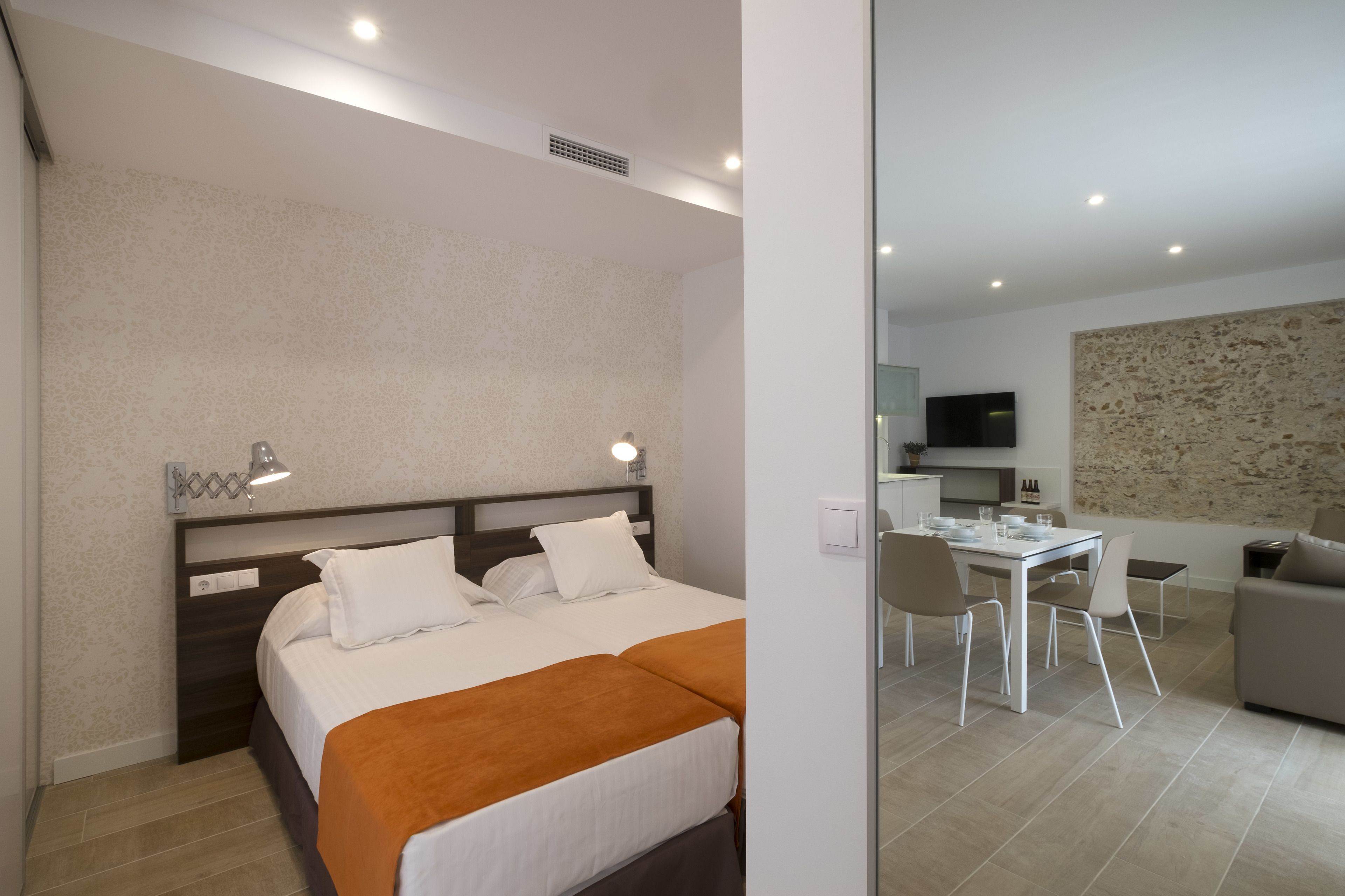A hotel room with a bed, bedside tables, a desk, and a sofa.