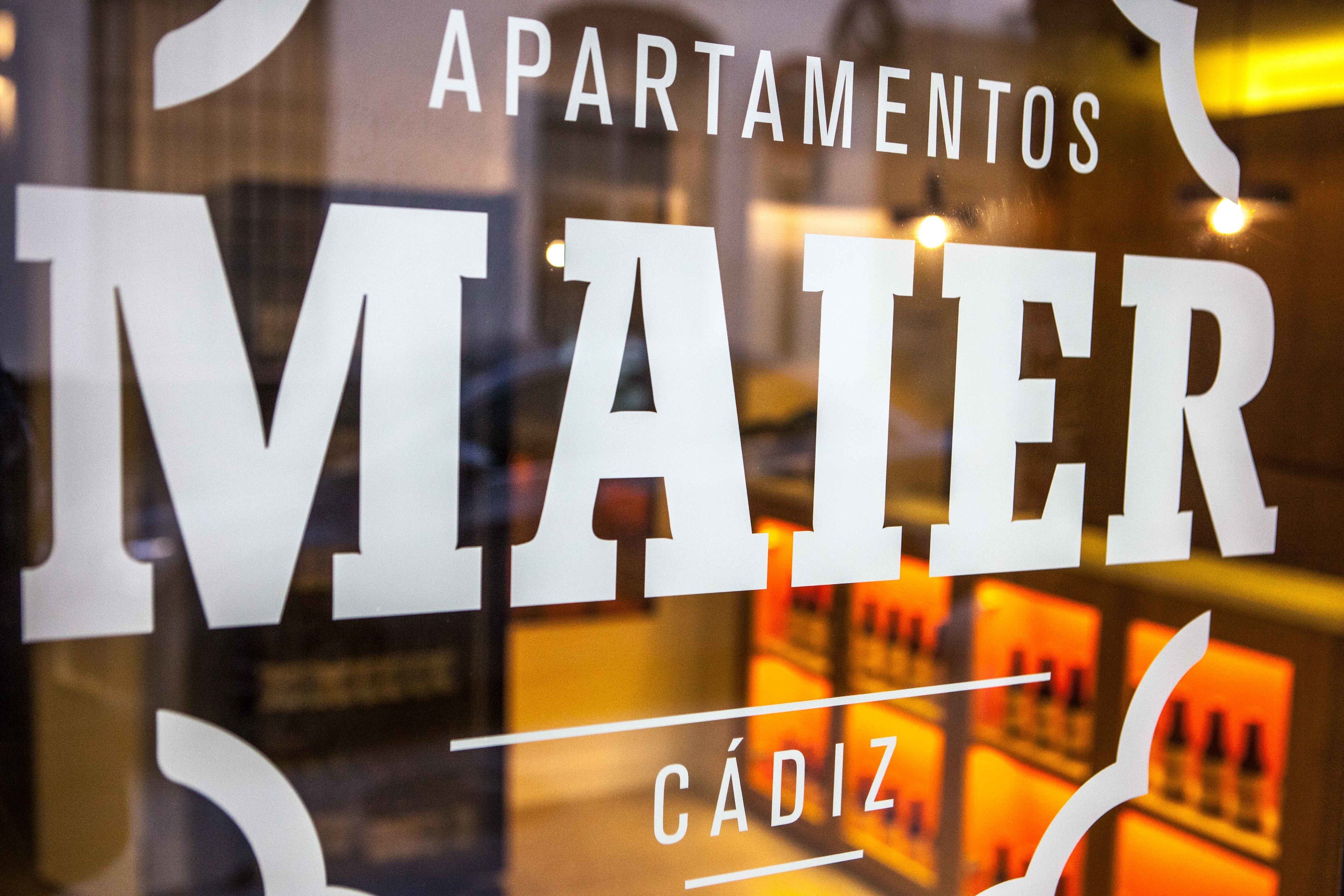 A sign with the words "APARTAMENTOS MAIER" and "CÁDIZ" indicating the name of a hotel or apartment complex.