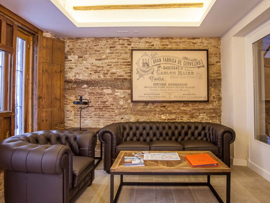 Una sala de estar moderna con un sofá de cuero, una mesa de centro y una pared de ladrillo con un letrero enmarcado.