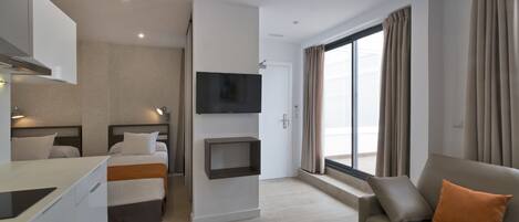 Una habitación de hotel moderna con cama, sofá, televisión montada en la pared y una mesita.