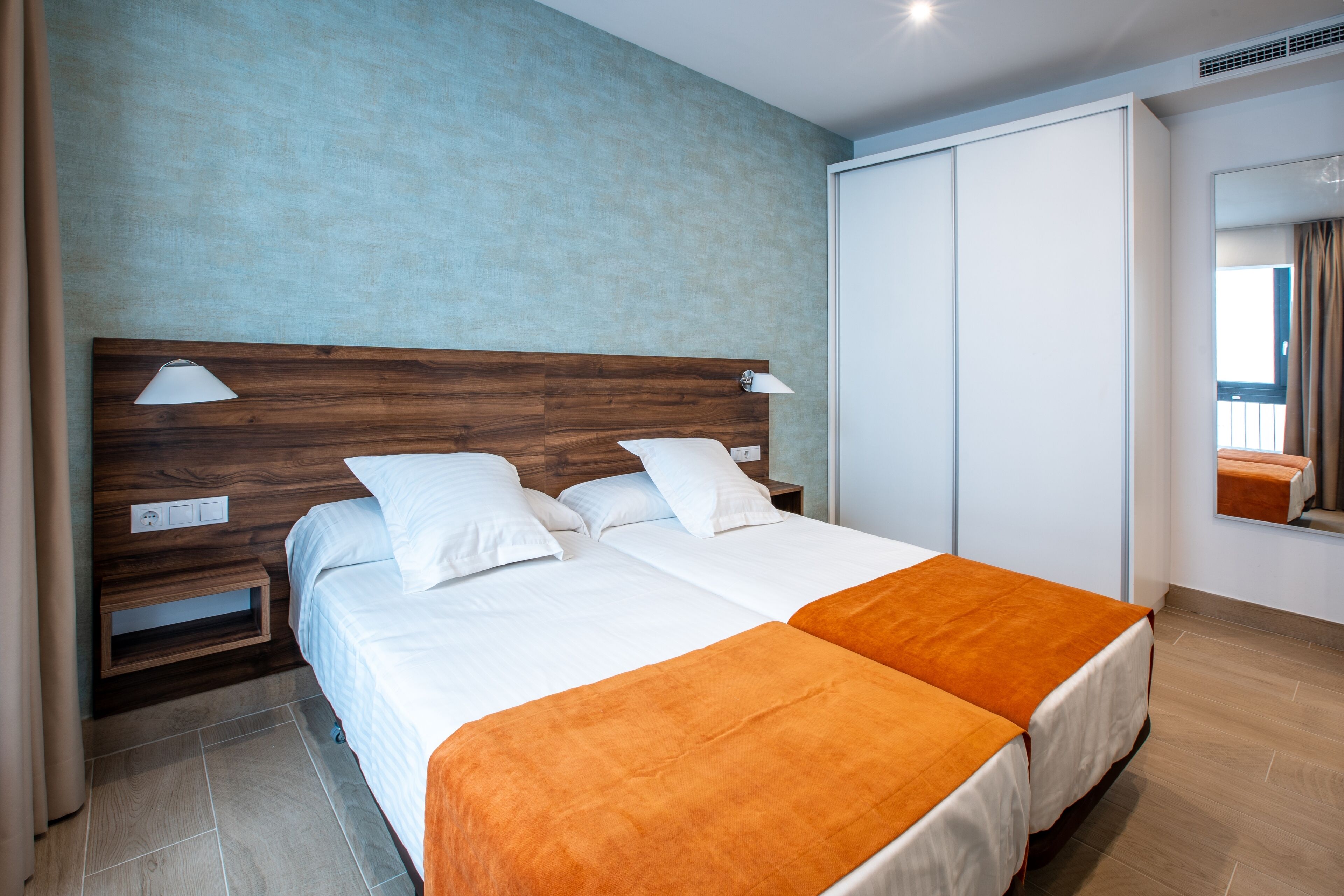 Una cama doble con cabecera de madera, dos mesitas de noche y una mesita auxiliar.