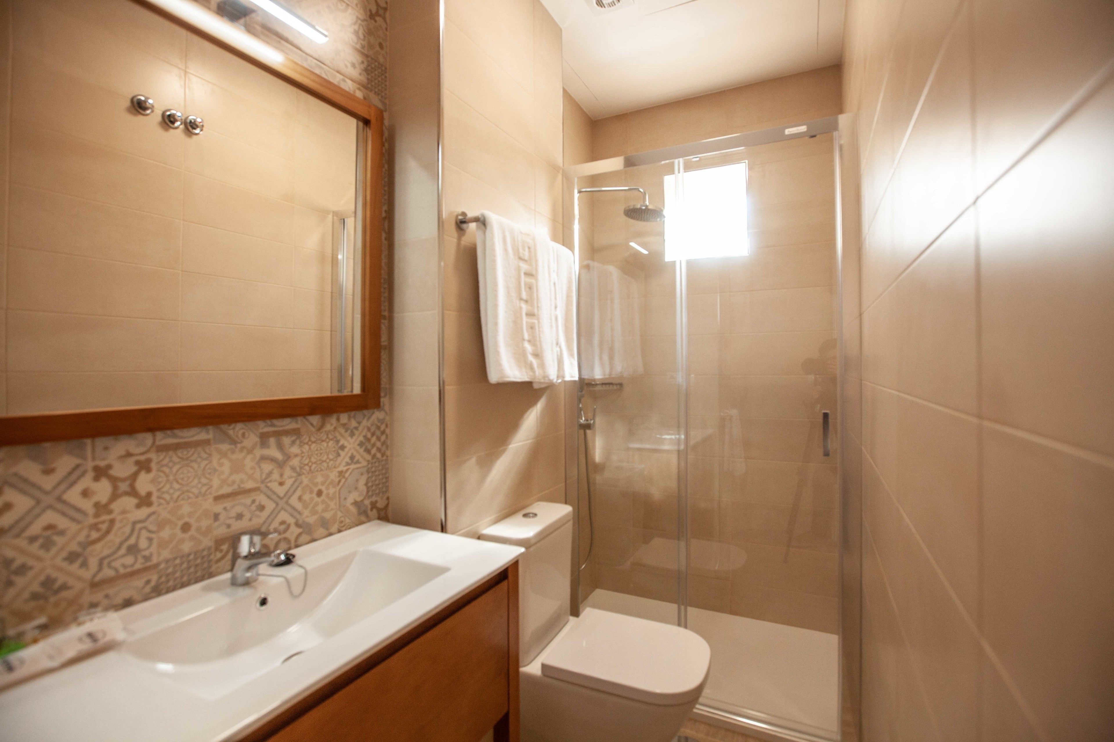 A bathroom with a sink, toilet, and glass-enclosed shower.