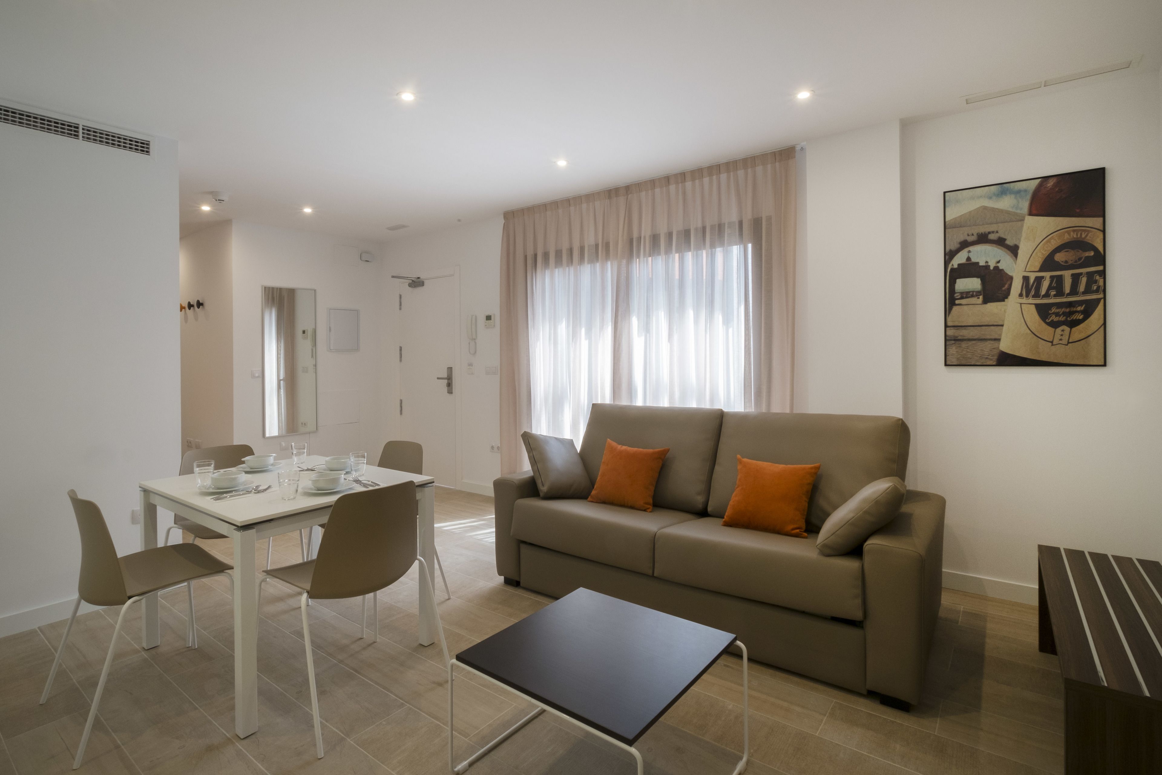 Una sala moderna con un sofá, una mesa de comedor para cuatro comensales y una pequeña mesa de centro.