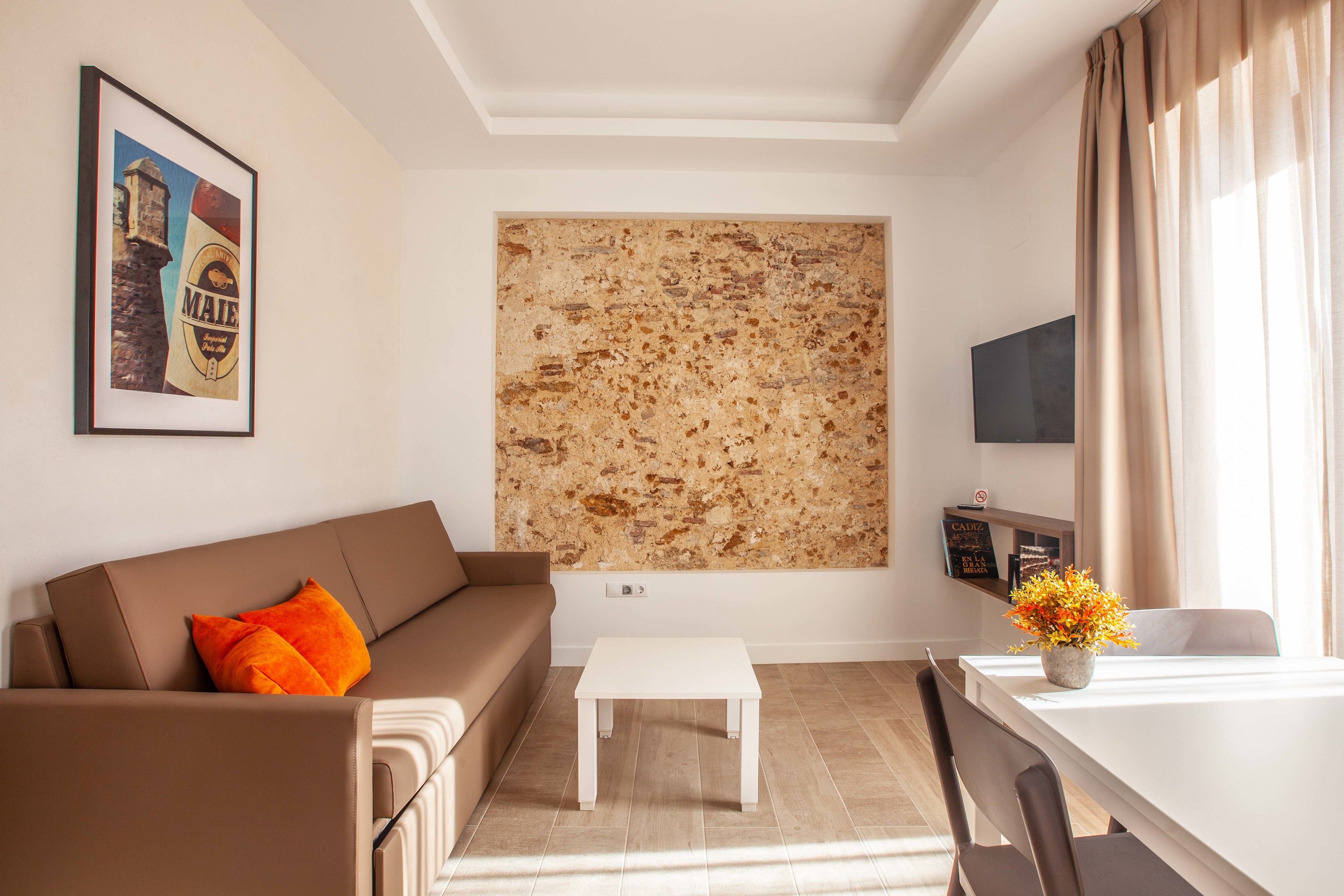 Een moderne woonkamer met een bruine bank, een witte salontafel en een eettafel met een bloevas.