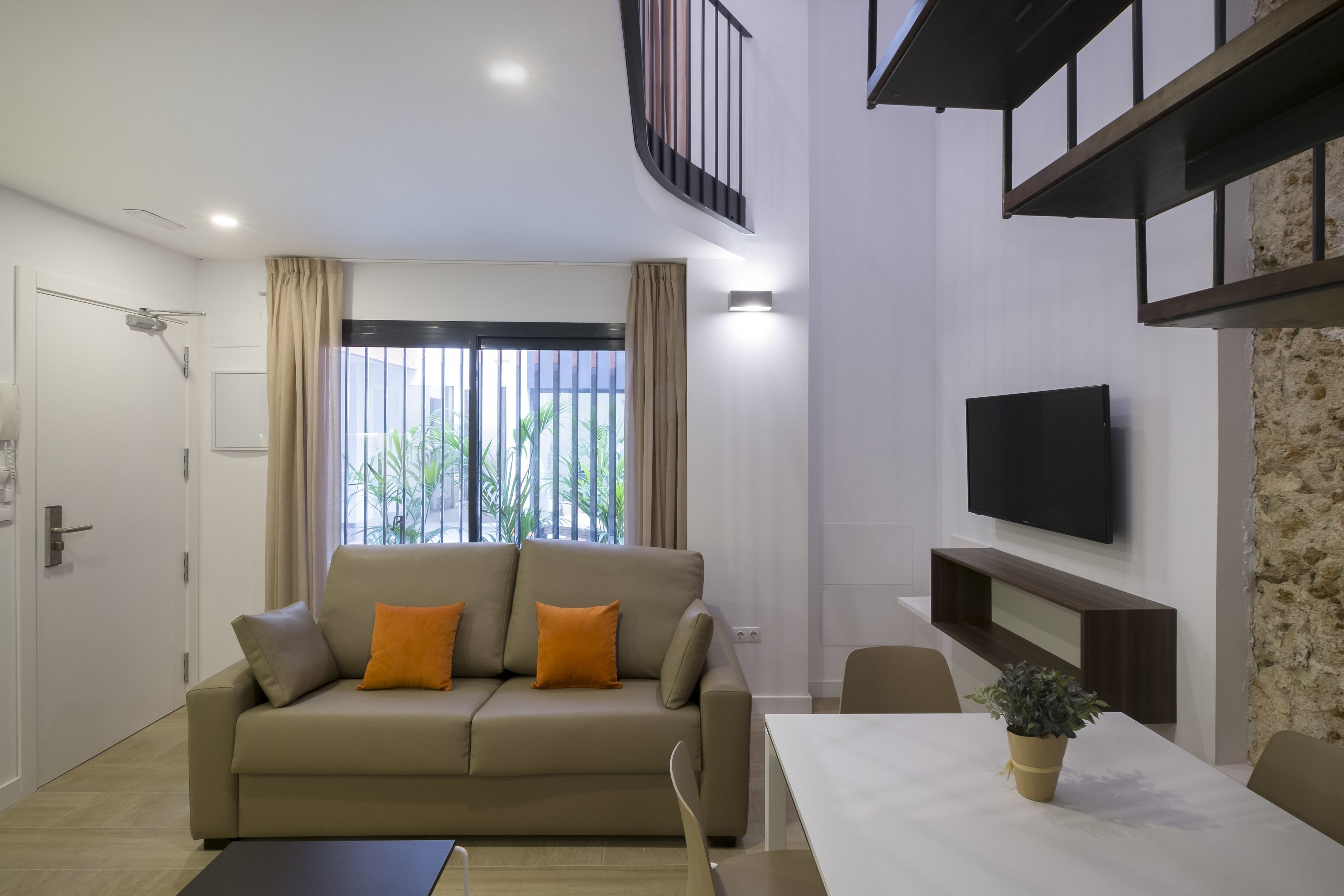 Una sala de estar moderna con un sofá, una mesa de comedor y un televisor.