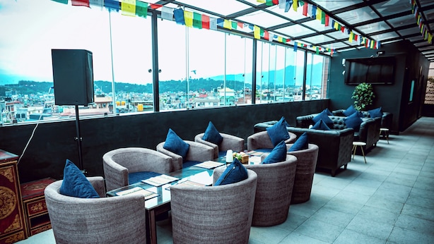 Eine Dachterrasse mit gepolsterten Sitzgelegenheiten, einem Flachbildfernseher und Blick auf eine Stadtlandschaft.