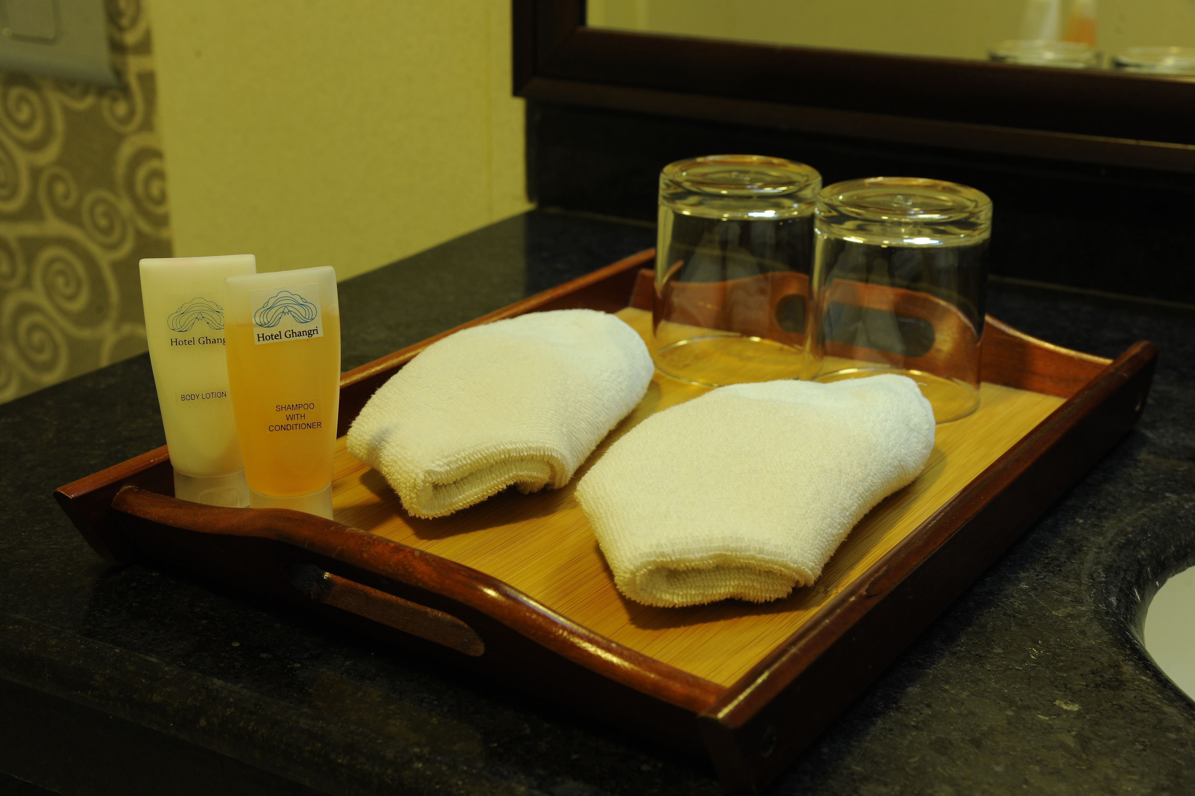 Una bandeja con artículos de aseo, incluyendo loción corporal, champú con acondicionador y toallas.