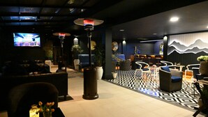 Eine moderne Lobby mit Schachbrettmuster-Boden, Sitzbereichen und einem Bildschirm.