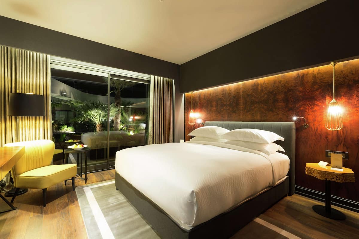 Une chambre d’hôtel moderne, dotée d’un grand lit, d’un bureau et offrant une vue sur l’extérieur.