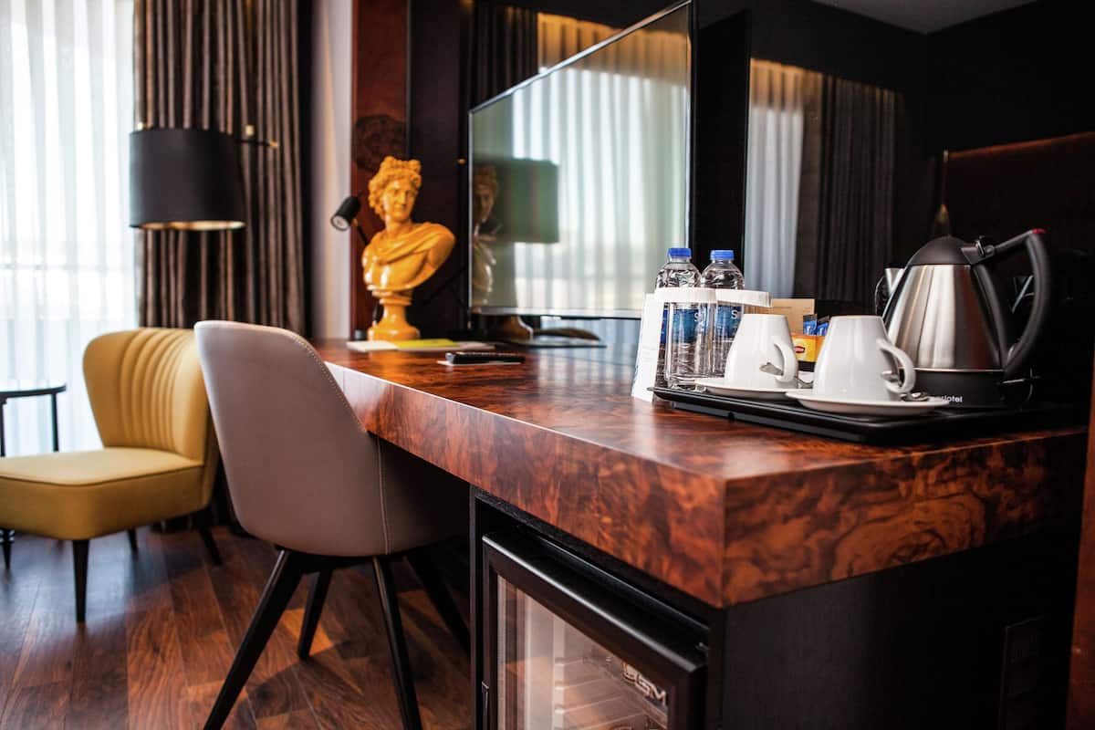 Une chambre d’hôtel dotée d’un comptoir en marbre, d’une statue, d’une télévision, d’une machine à café et d’un mini-bar.