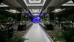 A formal event space with a central stage, rows of tables, and a chandelier.