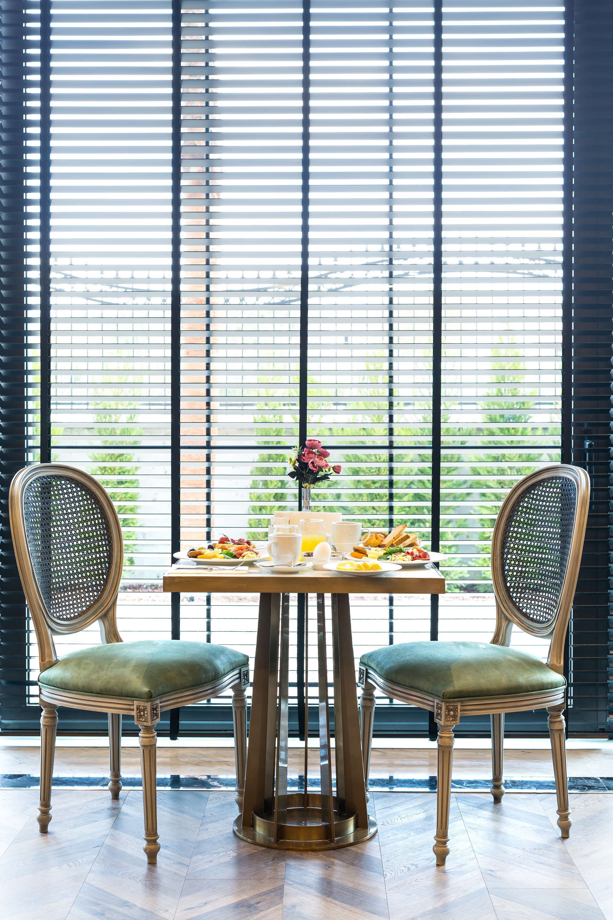Un comedor con una mesa dispuesta para dos personas, con un centro de mesa floral, platos de comida y bebidas.