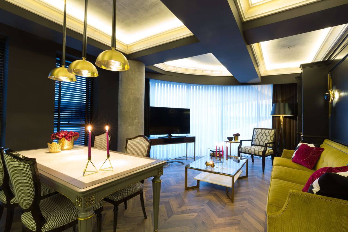 Un salon moderne avec un coin repas, comprenant un canapé, des fauteuils, une table basse et un téléviseur.