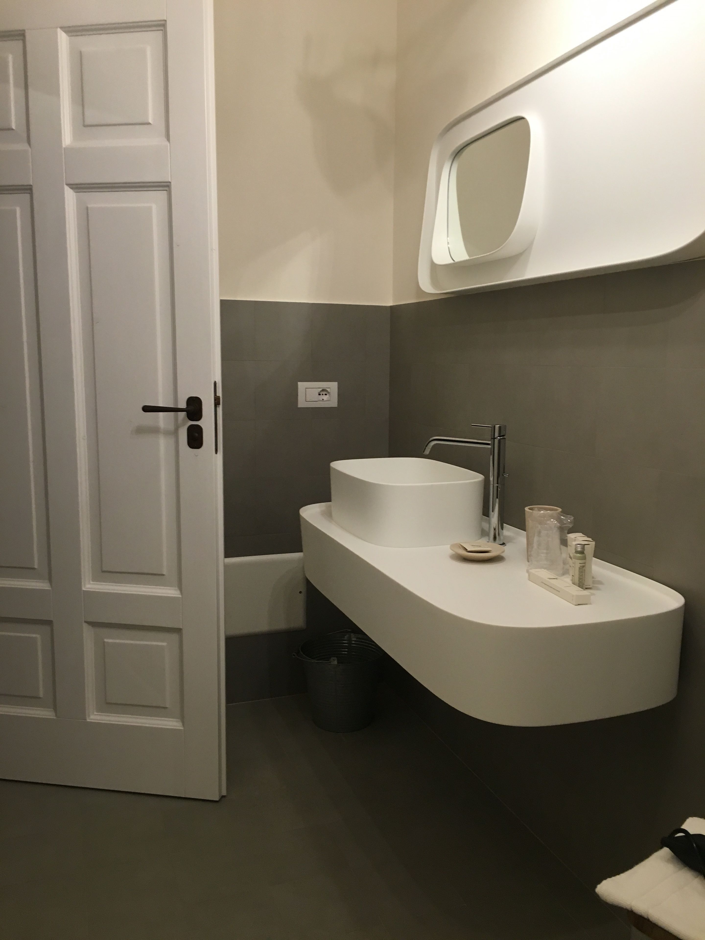 Un baño con un lavamanos blanco, un espejo y una puerta.