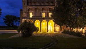 A castle-like building with arched windows and a tower at the back. - Vinilia Wine Resort (Manduria)