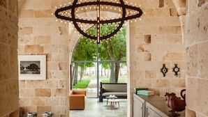 An arched corridor with patterned flooring, a hanging light fixture, and a view of an outdoor seating area. - Vinilia Wine Resort (Manduria)