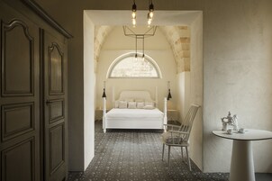 Un dormitorio con una cama grande, una silla, una mesa y una araña.
