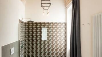 A bathroom with a shower, toilet, and a red chair.