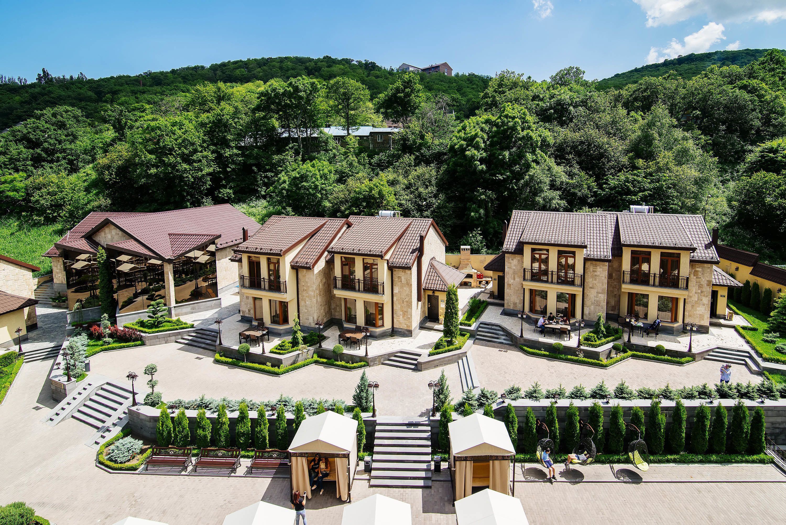 A hotel with multiple buildings, a central courtyard, and a mountainous backdrop.