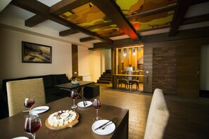 A dining area with a wooden table set for a meal, featuring a cheese platter and wine glasses. - Elegant Hotel & Resort (Tsaghkadzor)