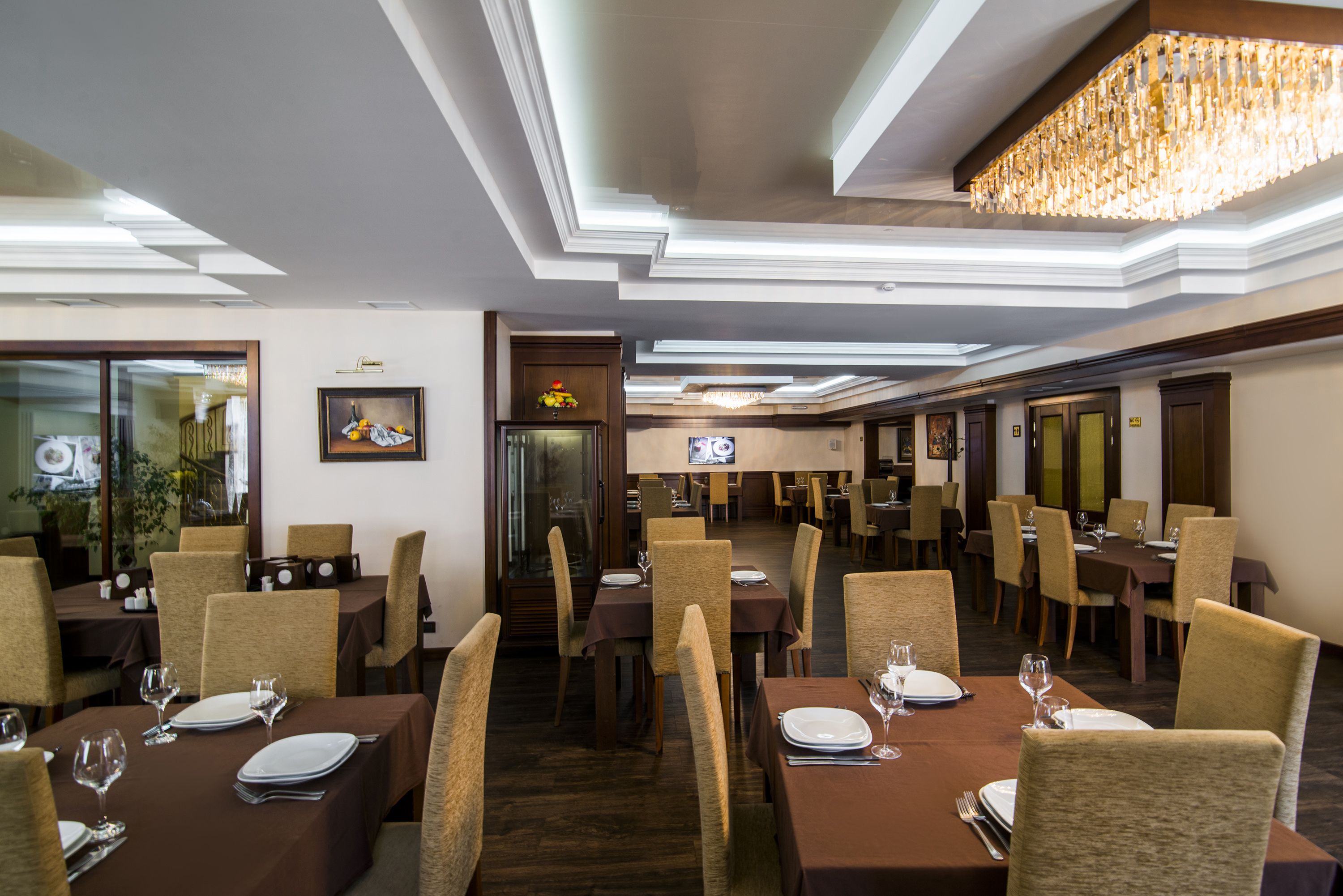 A restaurant with multiple dining tables, chairs, and a chandelier.